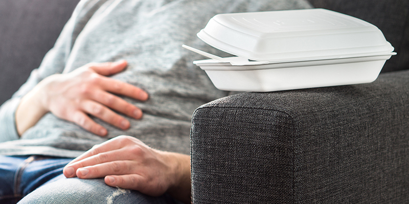 Uomo sul divano con la mano poggiata sulla pancia