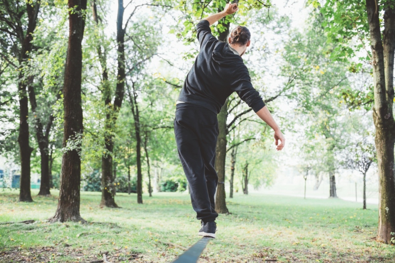 Ragazzo di spalle in un parco che è in equilibrio su una sbarra metalica