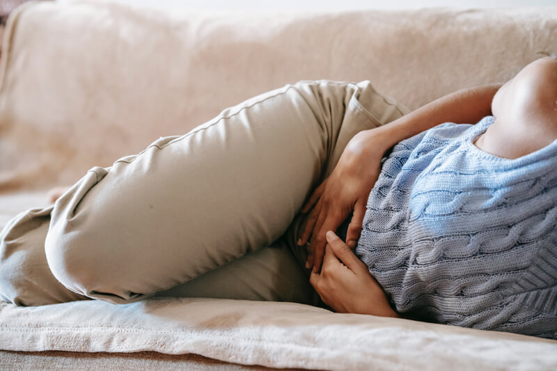 Donna distesa su una poltrona con le mani sulla pancia