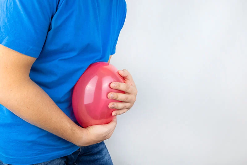 Dettaglio di busto maschile che stringe sulla pancia un palloncino rosso