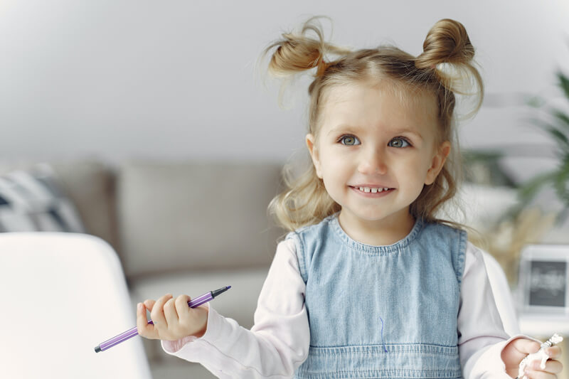 Bambina che ha in mano un animaletto in plastica e un pennarello viola